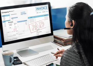 karyawan mengecek invoice di komputer